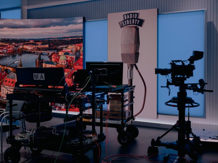 A studio with recording equipment and a large banner on the wall featuring a microphone and the words Radio Liberty