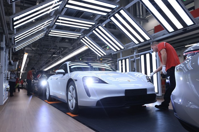 Staff check all-electric Porsche Taycan cars on the production line at the Porsche AG factory in Stuttgart, Germany