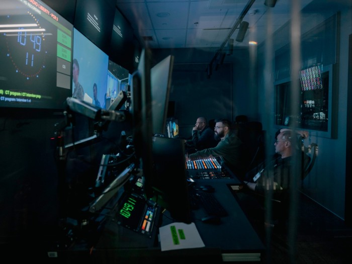 Three men in a studio full with recording equipment and screens