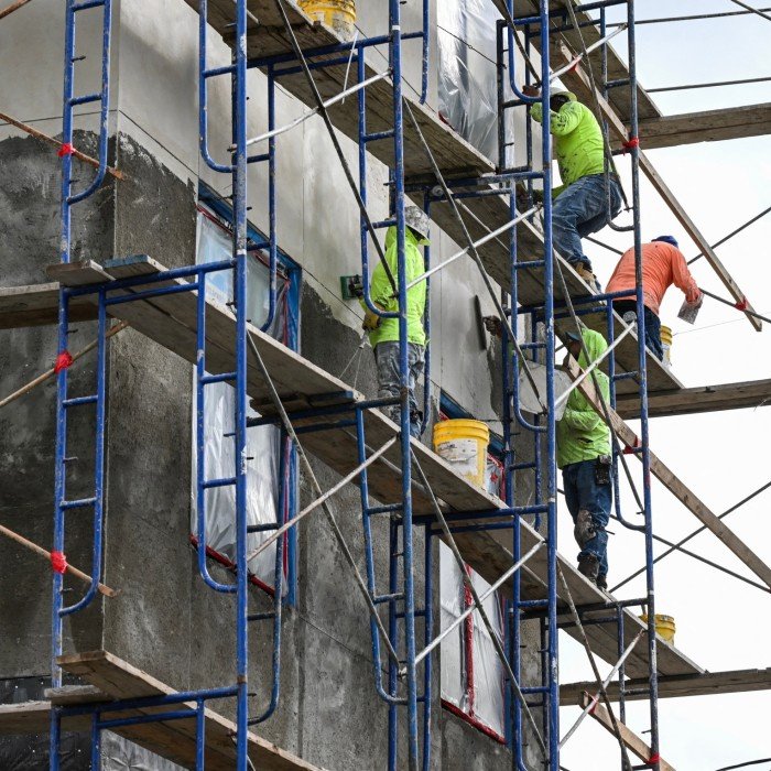 Construction workers stand on scaffolding